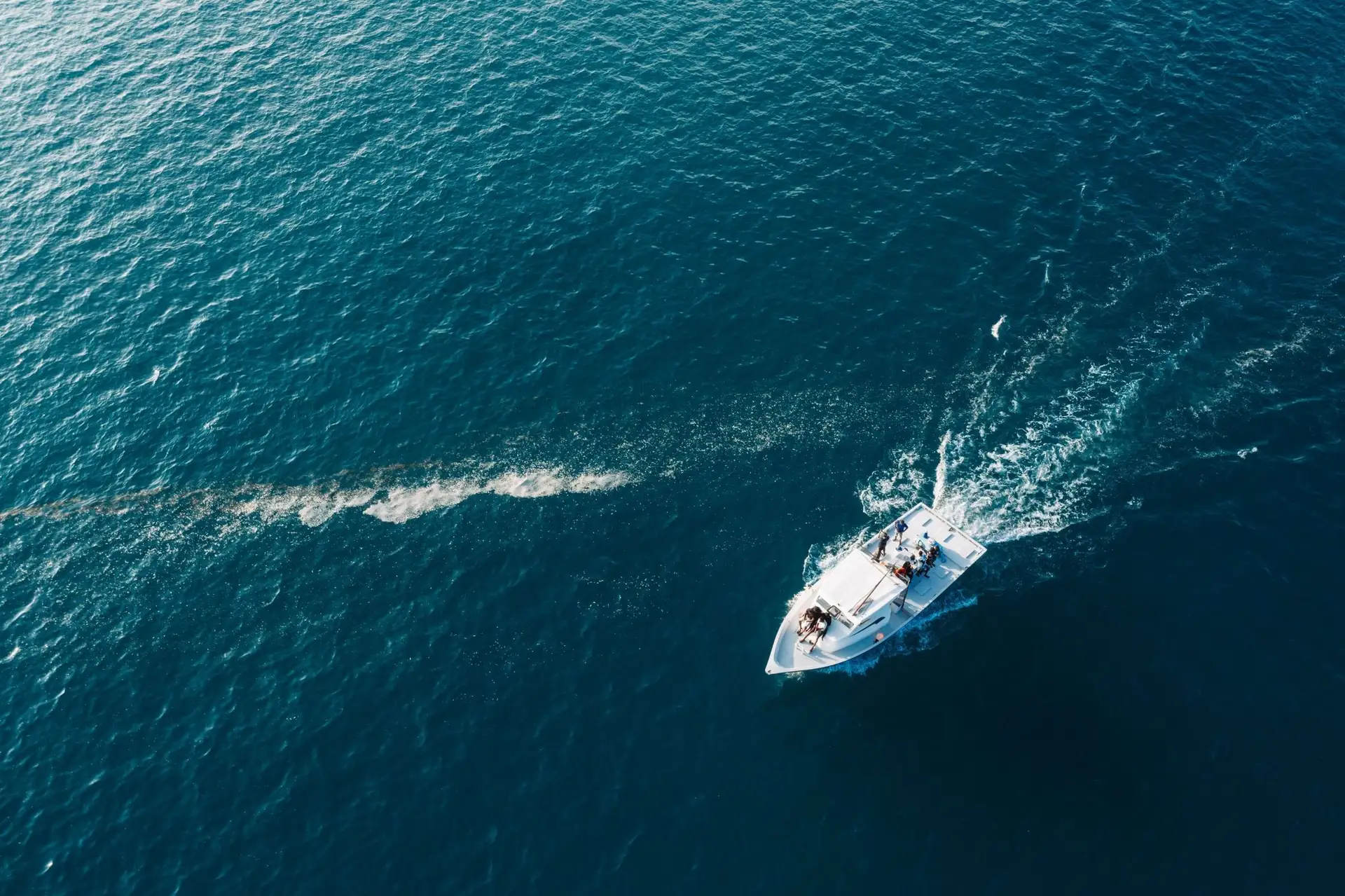 Aerial view of a boat carving a wake across open blue water